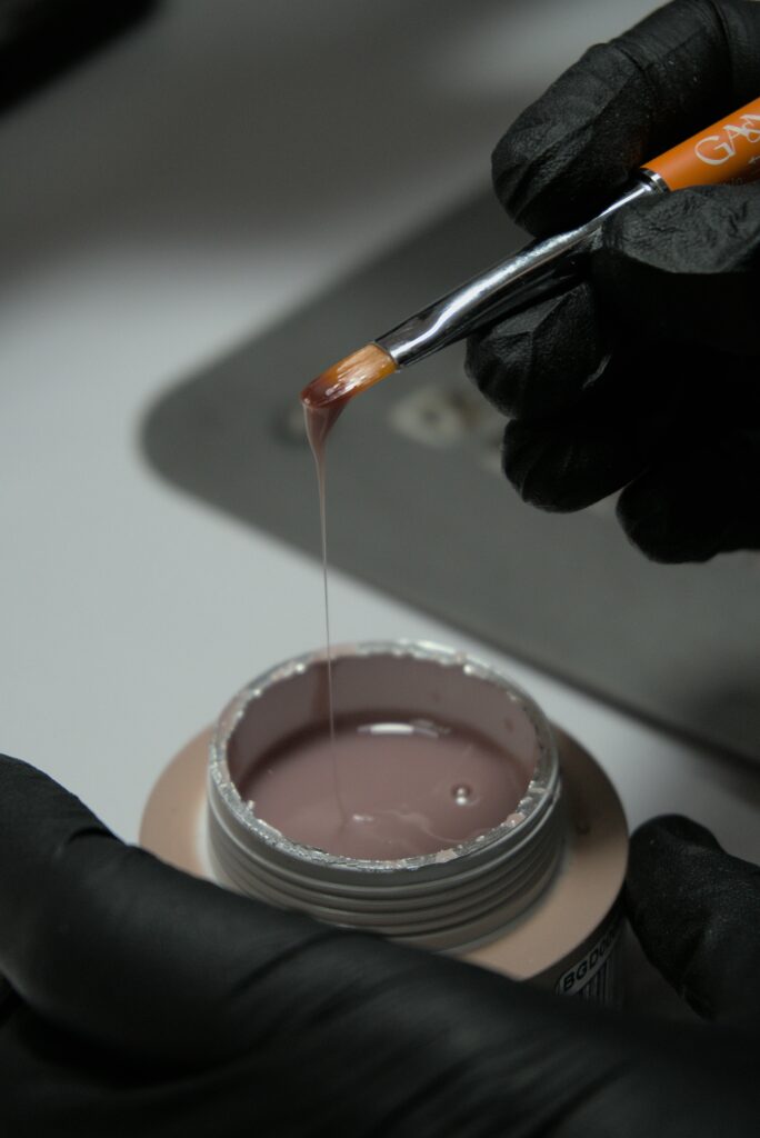 Detailed view of nail gel application with brush, showcasing beauty and care.